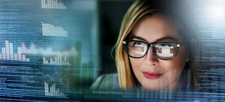 Woman wearing glasses looking at a computer screen processing data.