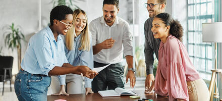 Group of people actively engaging in teamwork standing around a desk